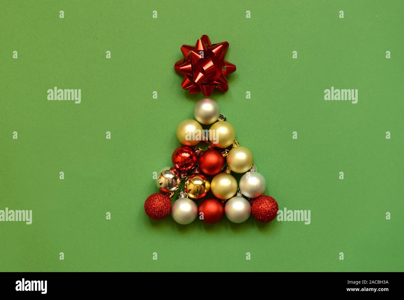 Christmas tree shape made with bauble on green background. Minimal holiday concept. Creative flat lay. Stock Photo