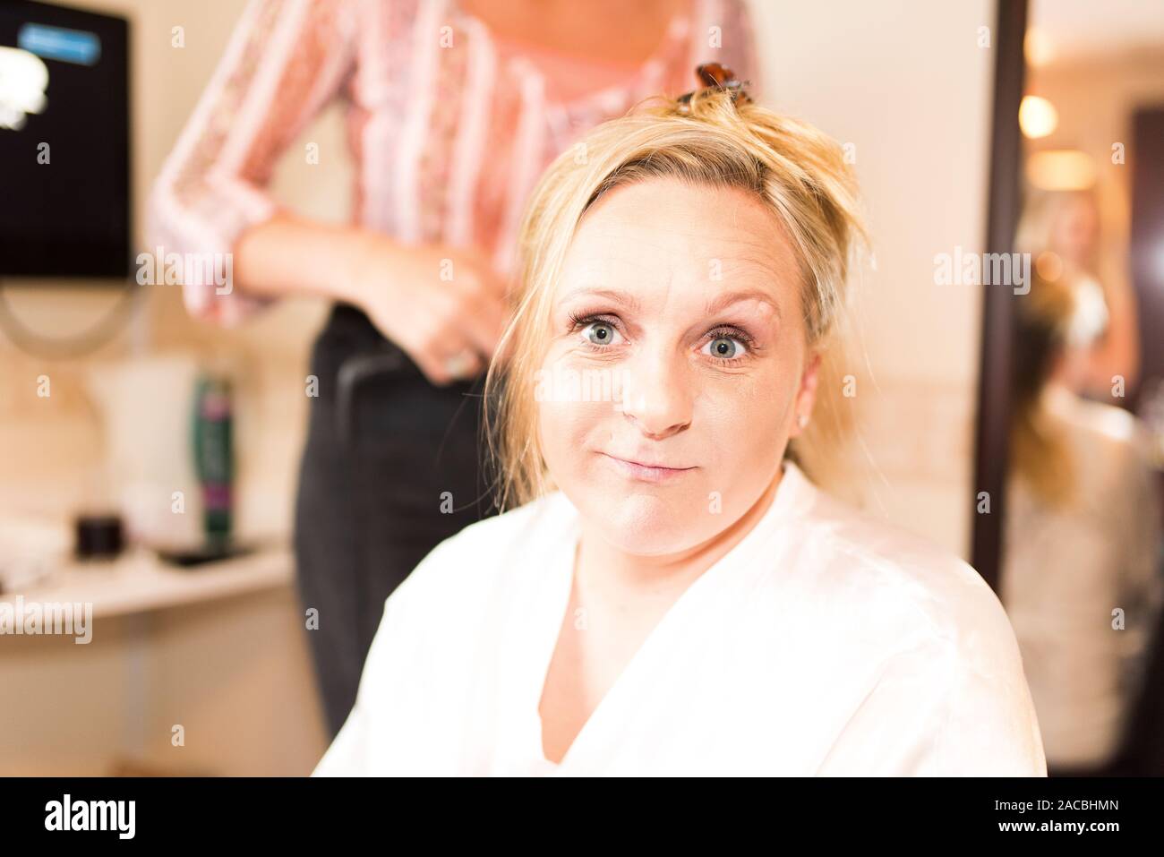 A pretty, cute young women getting reading for her big day during bridal preparation, make up artists and hair dressing with her bridesmaids Stock Photo