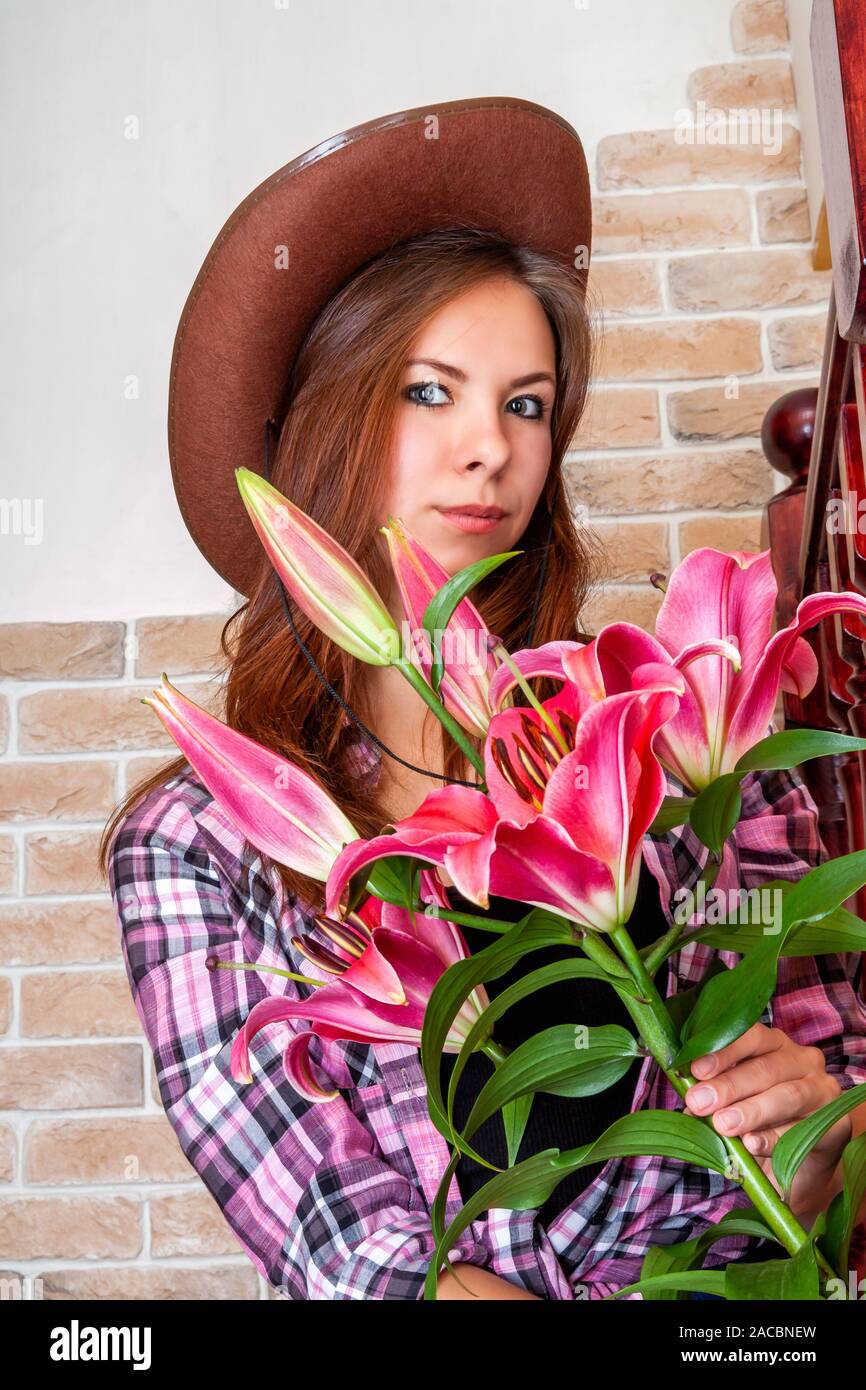 Attractive Girl In A Cowboy Hat With Straight Long Hair Holds Lily