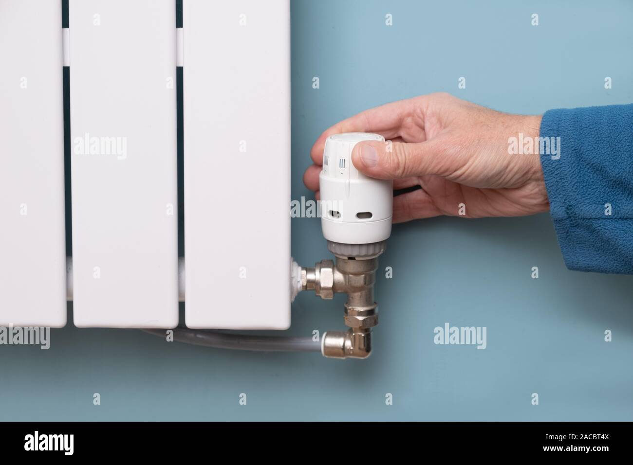 Hand turning down temperature on TRV radiator thermostat valve Stock Photo