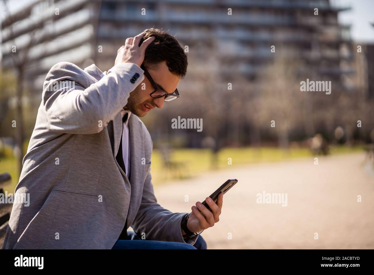 Young businessman is using smartphone in park. Stock Photo