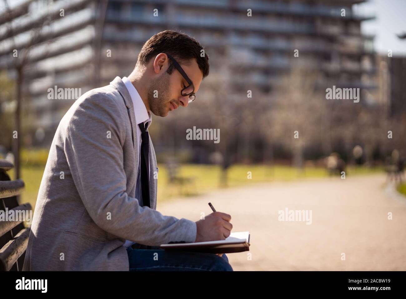 Young businessman is sitting in park and making plans. Stock Photo