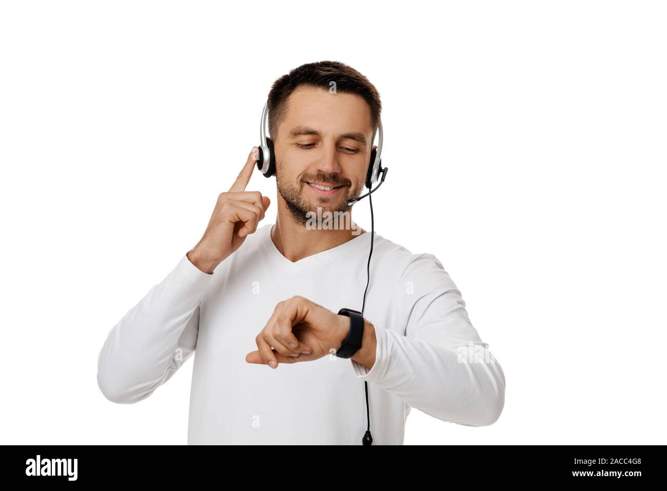 Call center worker man isolated on white background. Young smiling cute employee telesales agent using headset and looking at watch. Save your time - call customer service support Stock Photo