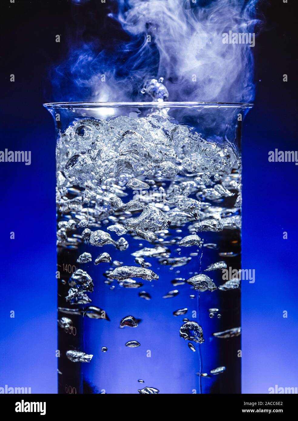 Boiling water in a tall beaker. Close up of escaping bubbles of steam