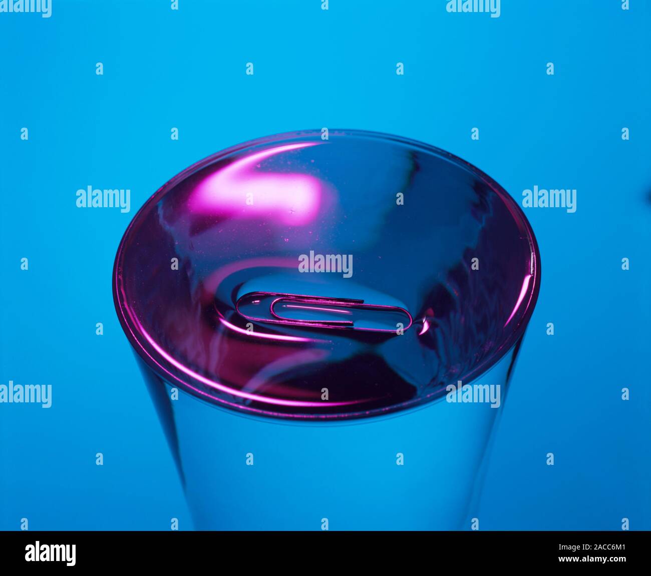 Surface tension. Paper clip floating on the surface of water as a