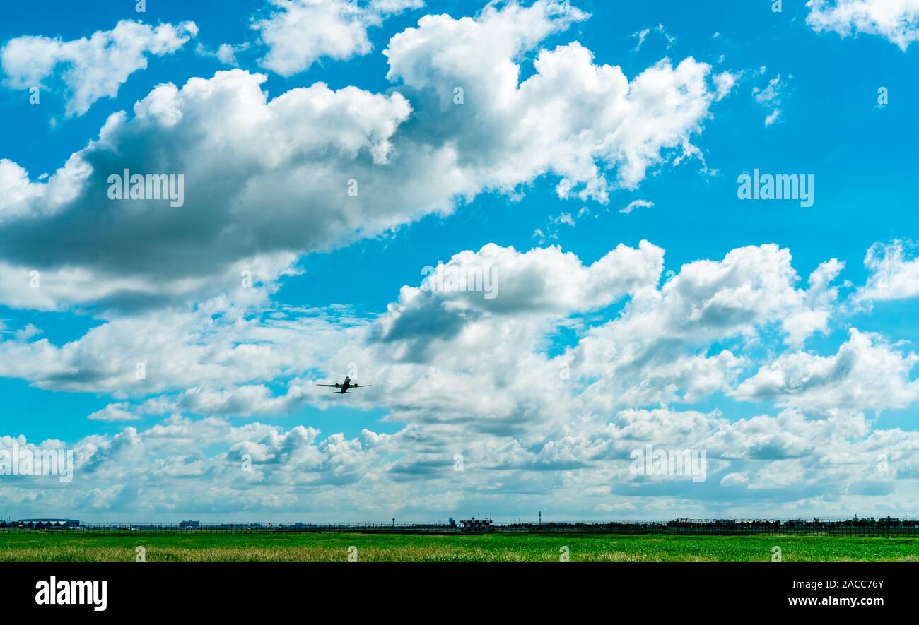 Commercial airline flying on blue sky and white fluffy clouds. Passenger plane after take off or going to landing flight. Vacation travel abroad. Air Stock Photo