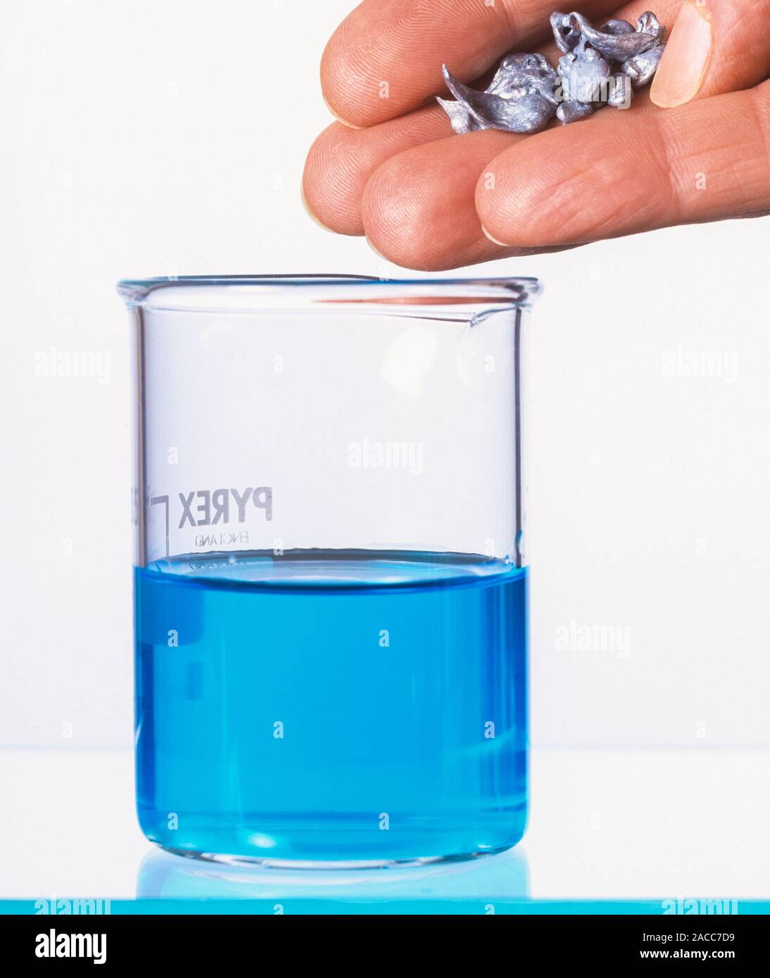 Displacement reaction. Image 1 of 2. Hand about to add zinc (Zn) metal