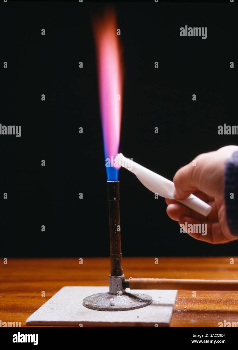 Flame test. Filter paper soaked in a solution of a lithium salt, burning in  the flame of a bunsen burner. The colour of the flame is caused by electro  Stock Photo -