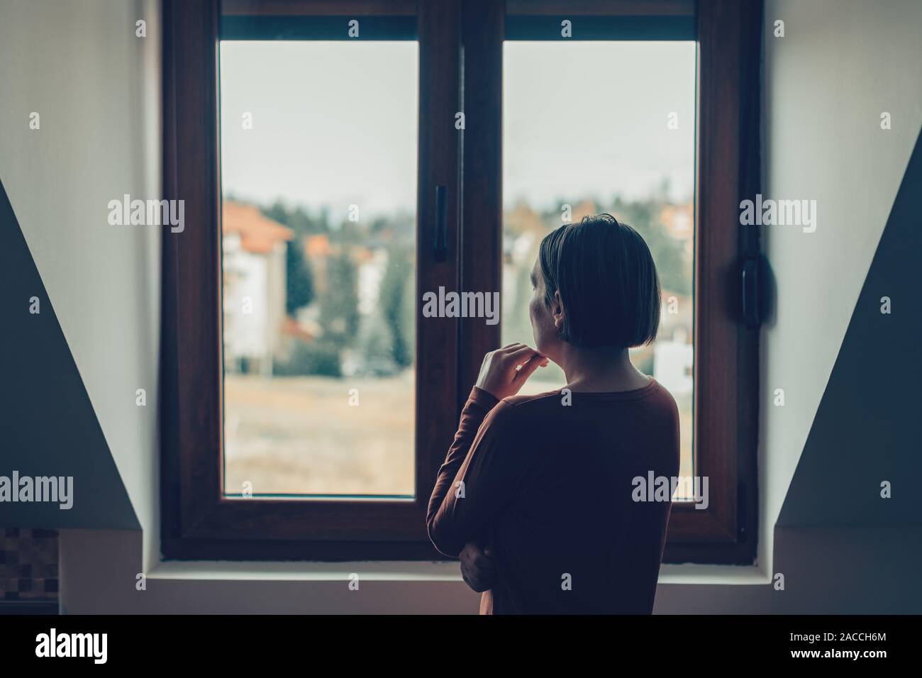 Sad woman looking out of the window in loft apartment Stock Photo