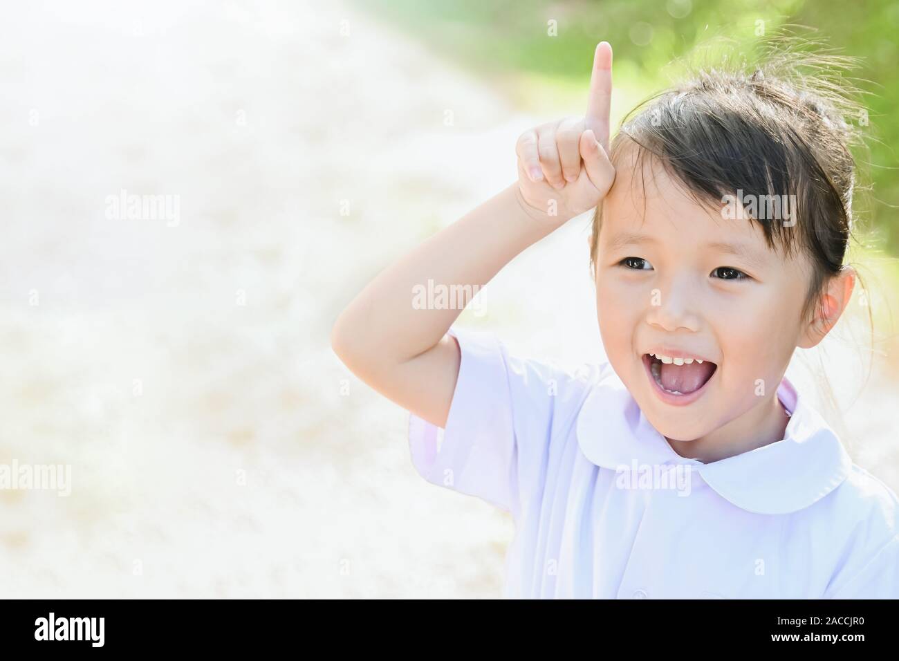 Little asian girl kid smiling with happy face and show up fingers sign Stock Photo