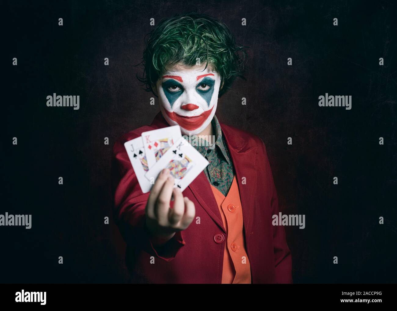 boy dressed as Joker with poker cards on dark background Stock Photo