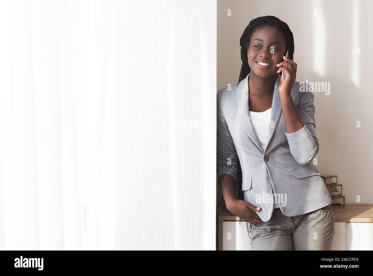 Black businesswoman talking on cellphone near window in office Stock Photo
