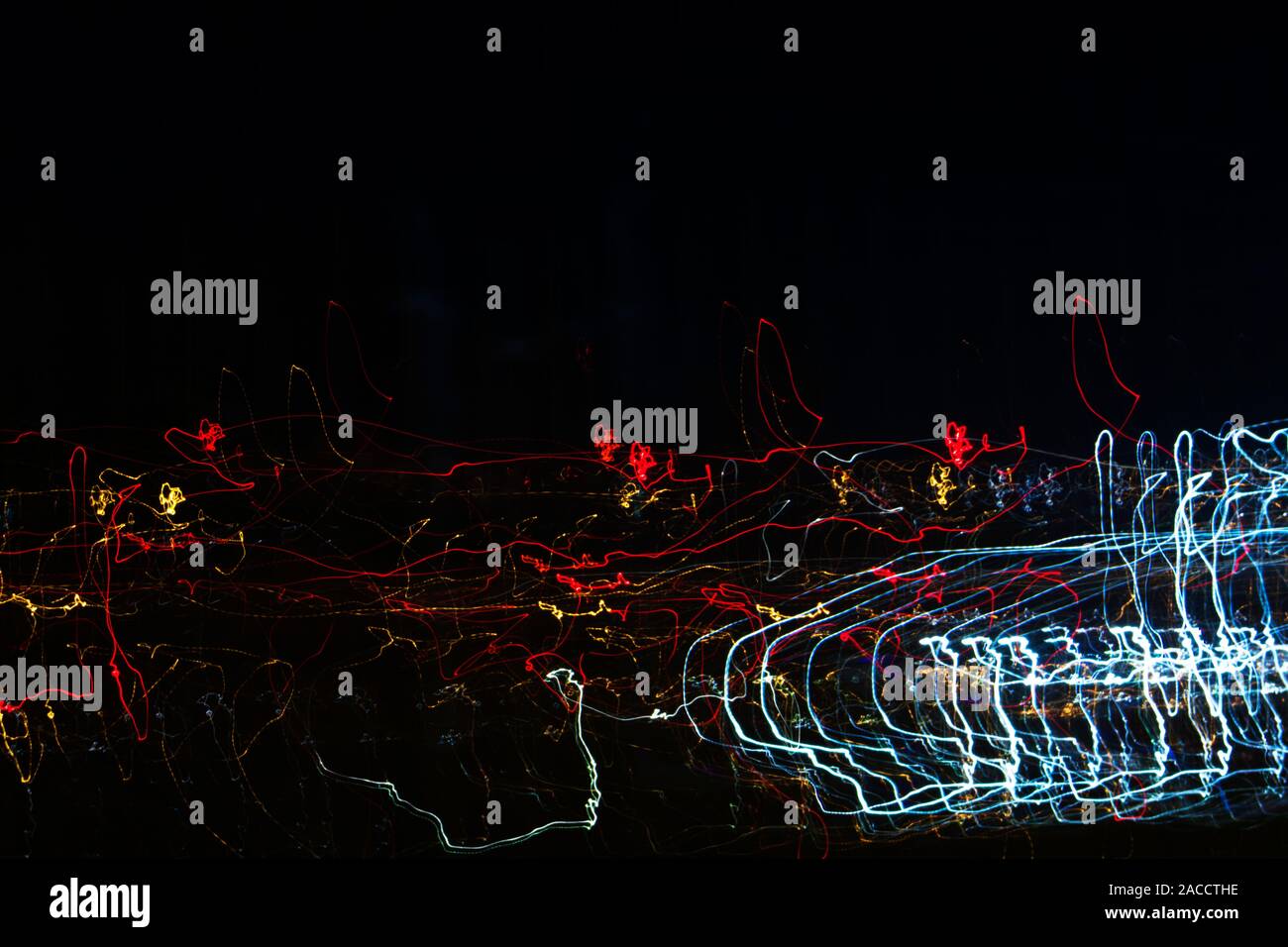 Different light trails of multicolored street lanterns and passing cars scattering in the dark, long exposure urban abstract background Stock Photo