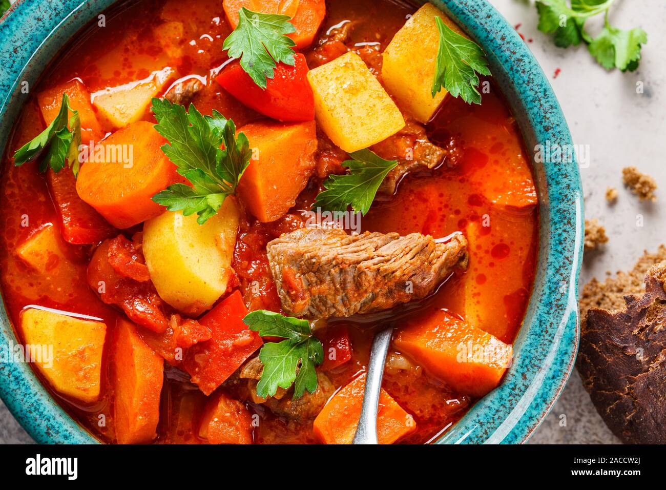 Traditional hungarian goulash. Beef stew with potatoes, carrots and paprika in a blue dish, top view. Stock Photo