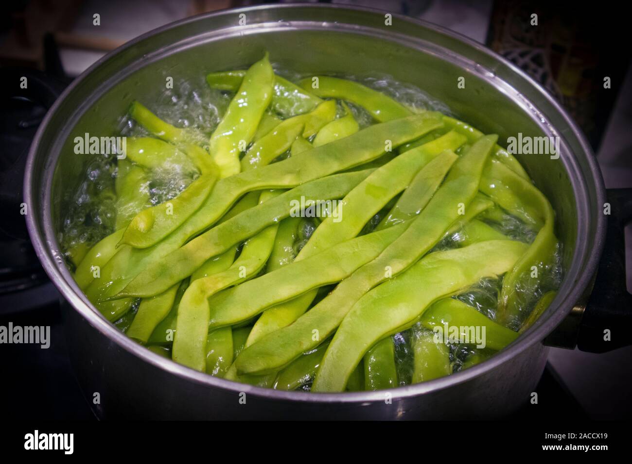 The top of large metal pan with boiling green bean pods inside Stock Photo