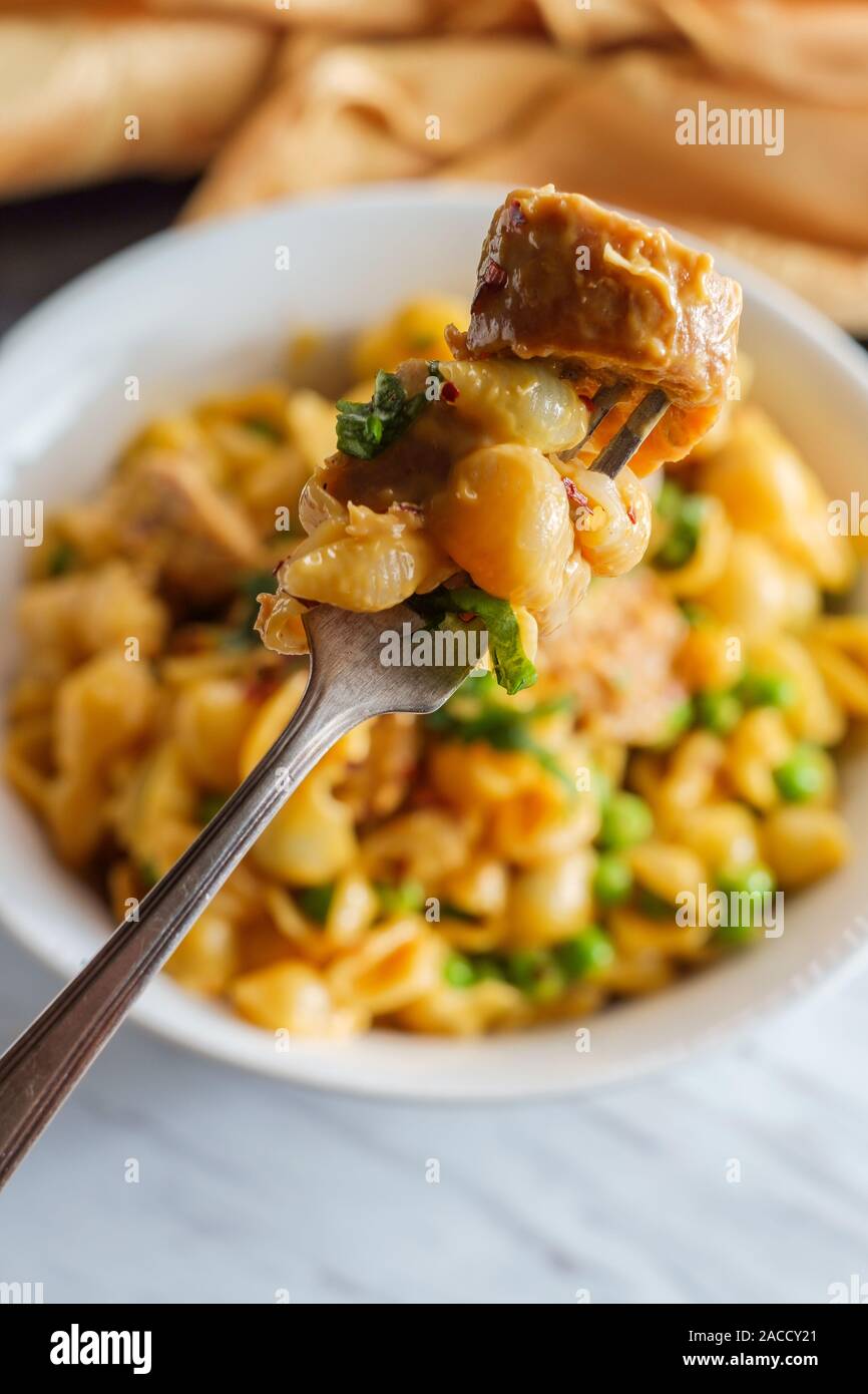 Sausage macaroni and cheese with green peas in bowl on marble kitchen table Stock Photo