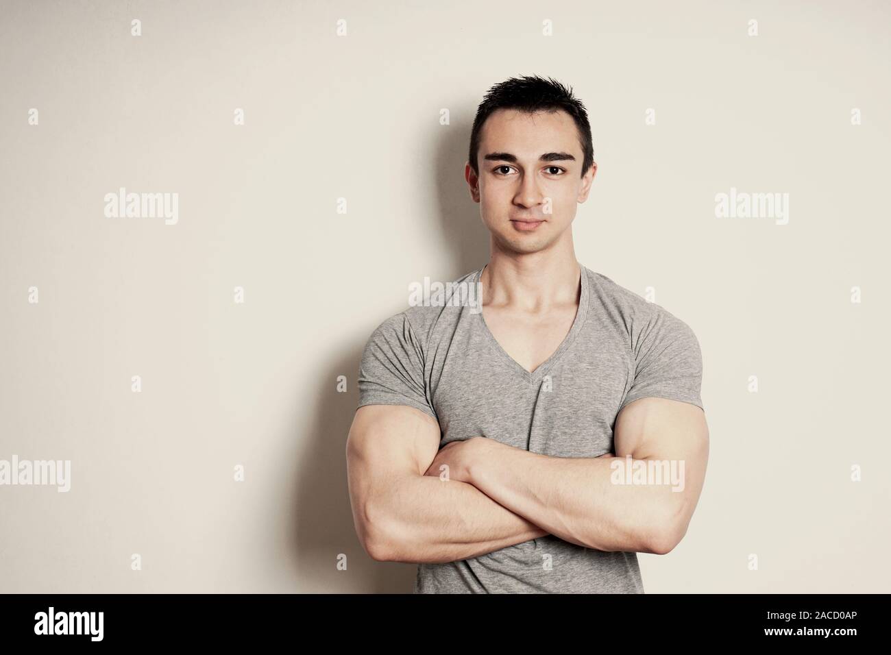 muscular young man with arms crossed standing against wall with copy space. vintage filter effect. Stock Photo