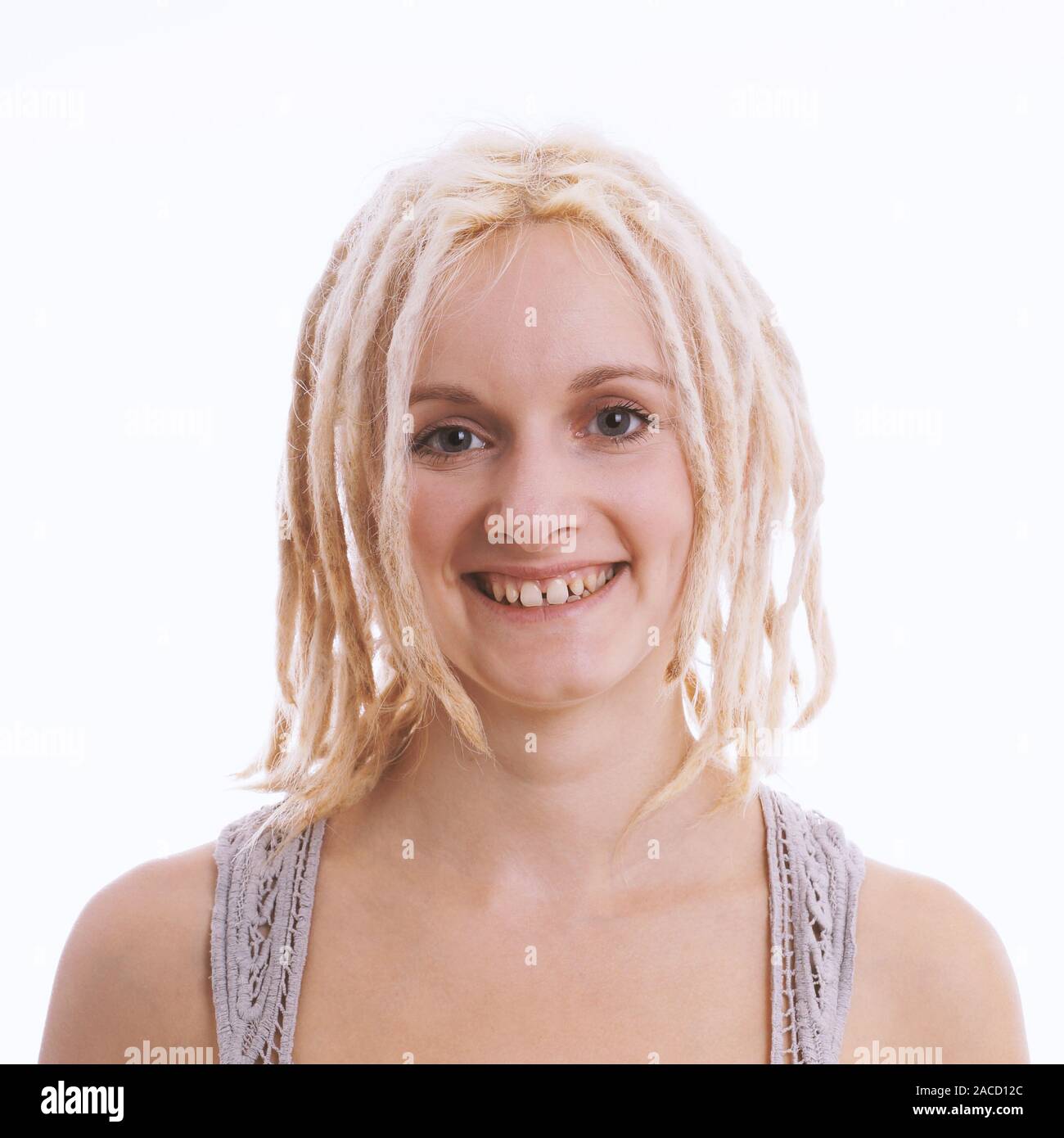 happy smiling young woman with blond dreadlocks and tooth gap - studio headshot against white background Stock Photo