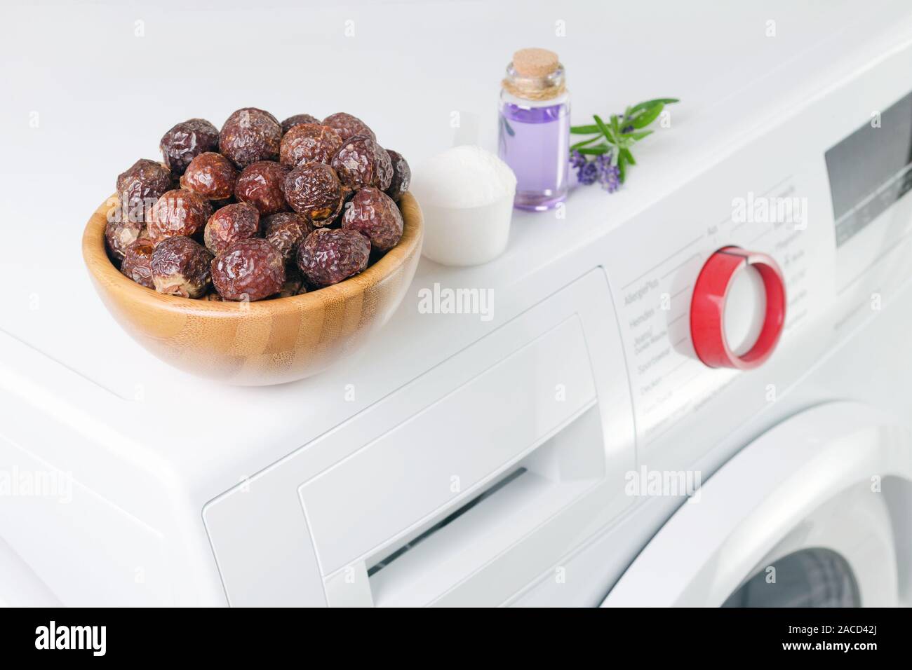 soap nuts in a bowl on the washing machine and lavender oil, detergent powder, selective focus Stock Photo