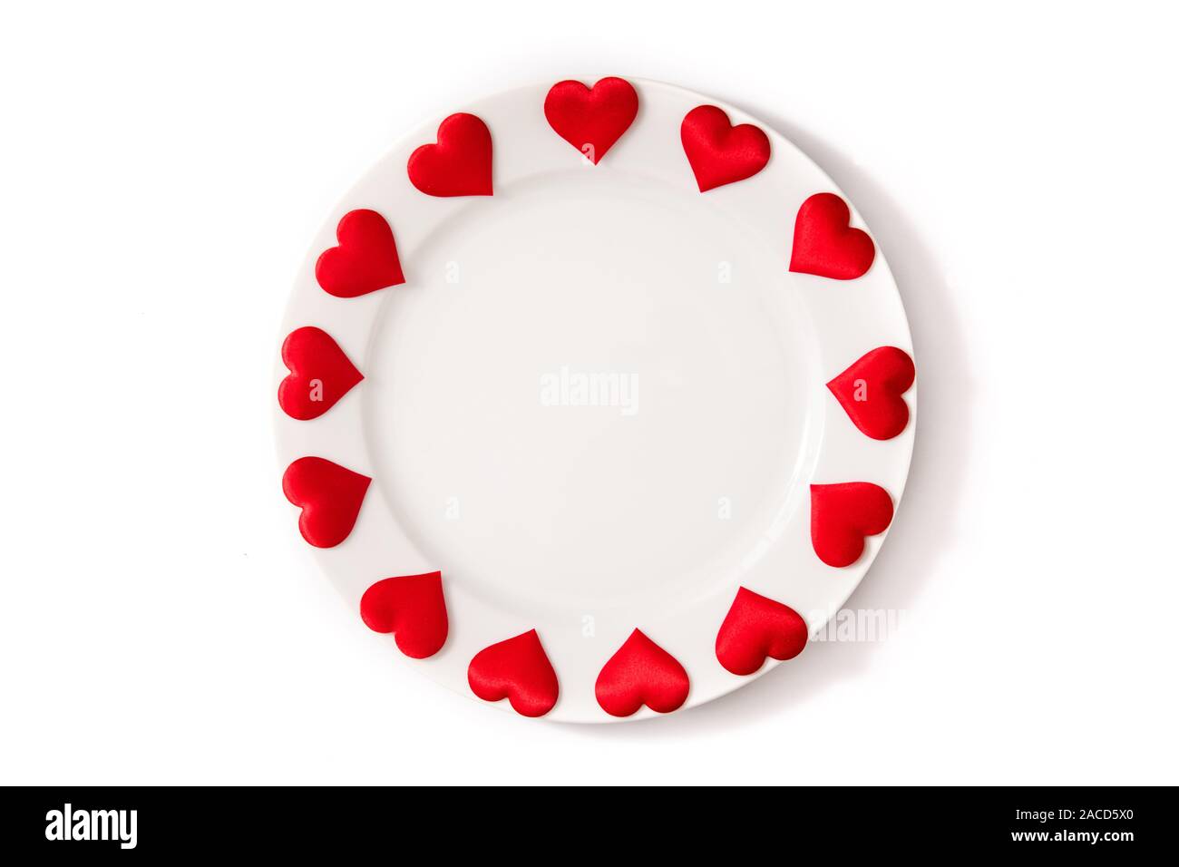 White plate surrounded by hearts on white background Stock Photo
