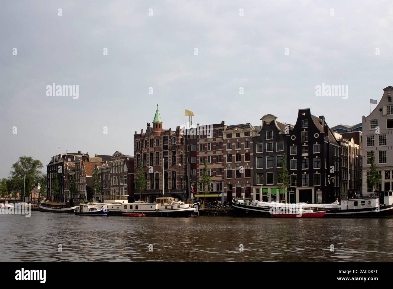 View of Amstel river, canal boats and historical, traditional and typical buildings reflecting Dutch architectural style in Amsterdam. It is a summer Stock Photo