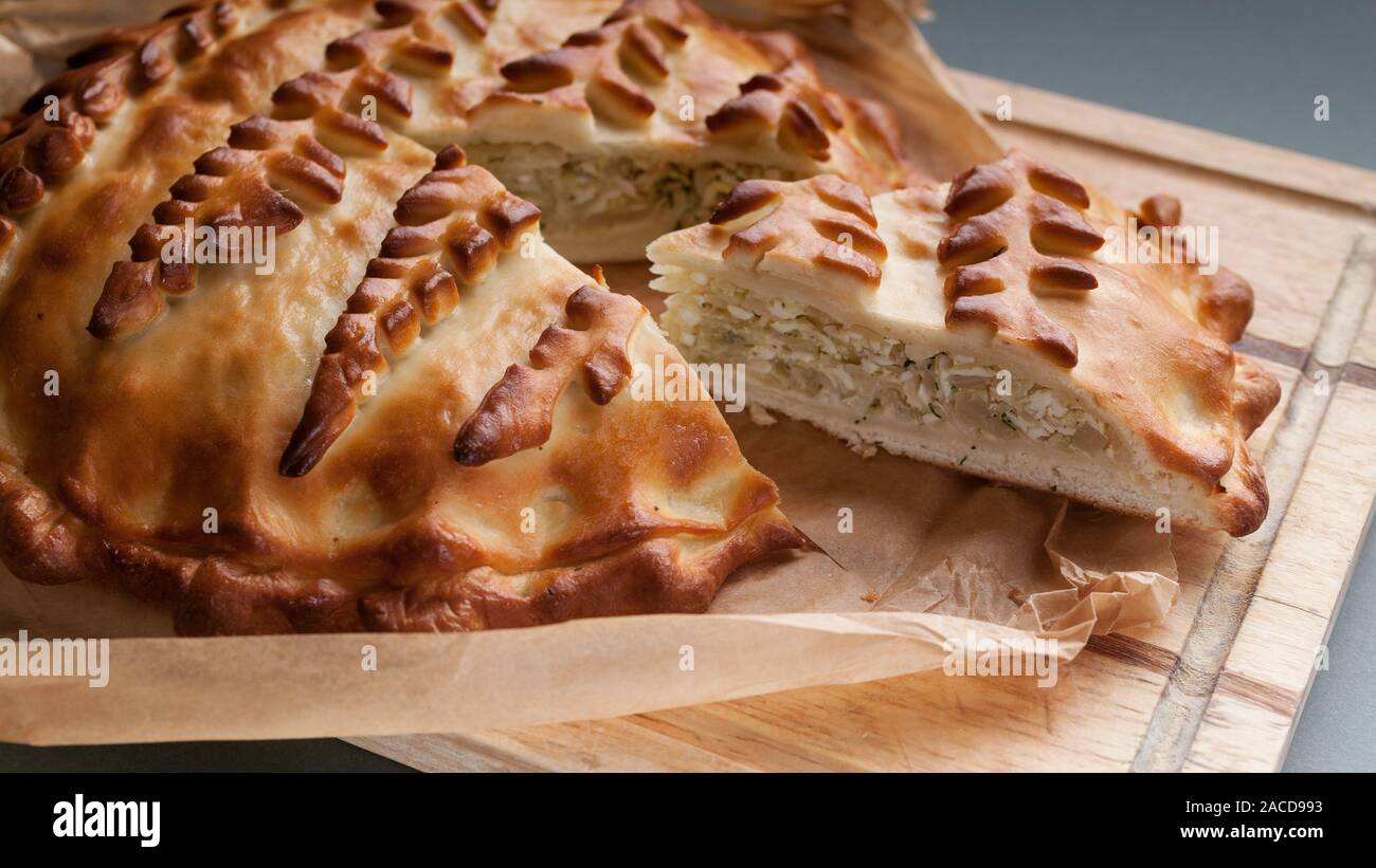 Close-up homemade cabbage pie on a cutting board. Russian and Ukrainian traditional national cuisine. Food Delivery Concept Stock Photo