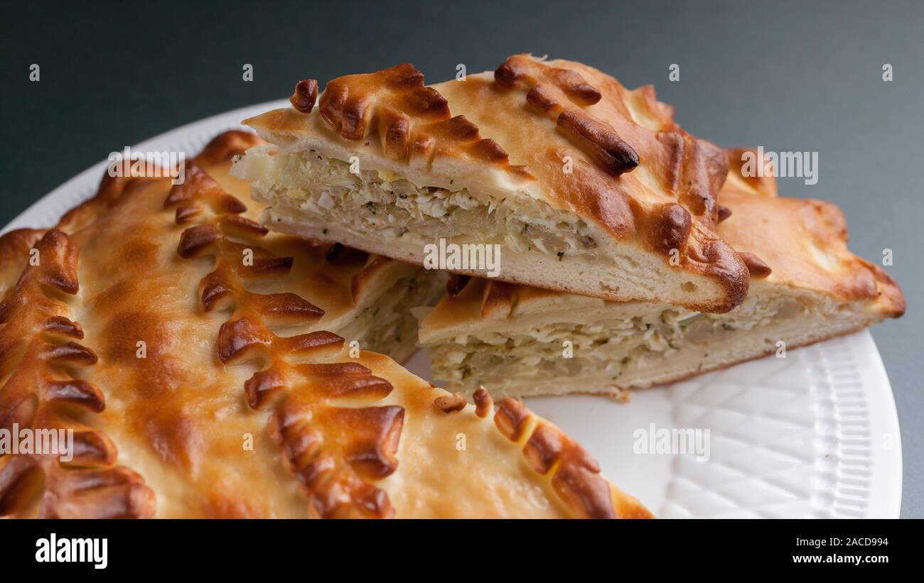 Close-up homemade cabbage pie on a white plate. Russian and Ukrainian traditional national cuisine. Food Delivery Concept Stock Photo