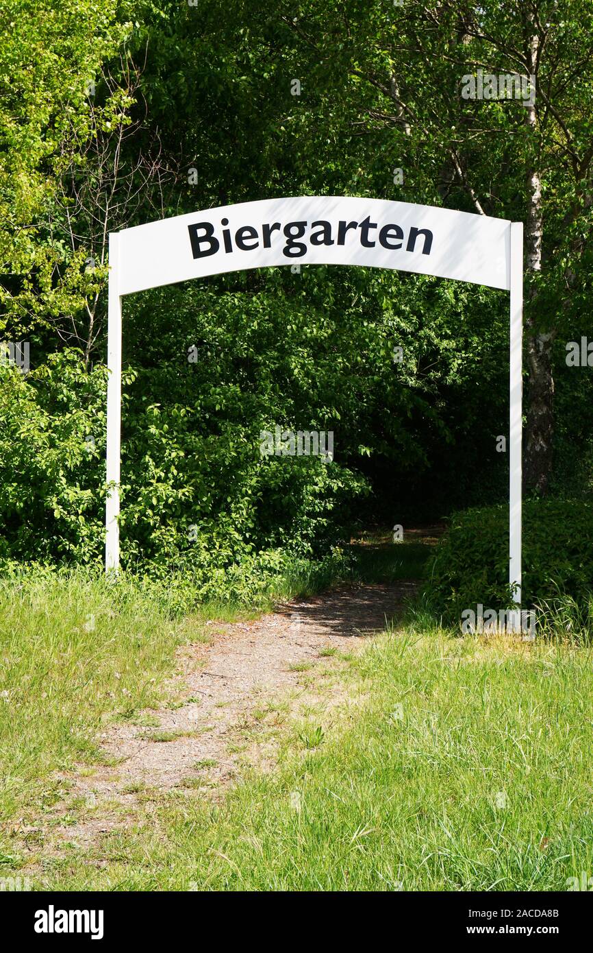 biergarten or beer garden in Germany - path leading through entry arch gate amidst trees Stock Photo