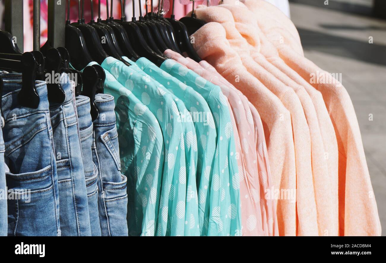 clothes rack with pastel-colored ladieswear spring fashion hanging outside retail store Stock Photo