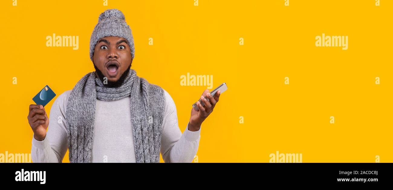 Amazed black man with smartphone and credit card Stock Photo