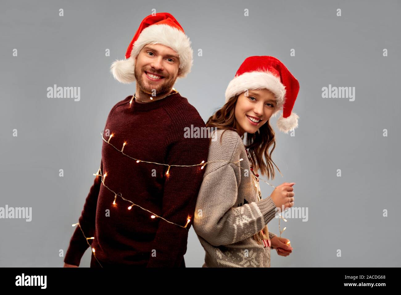 happy couple in christmas sweaters and santa hats Stock Photo