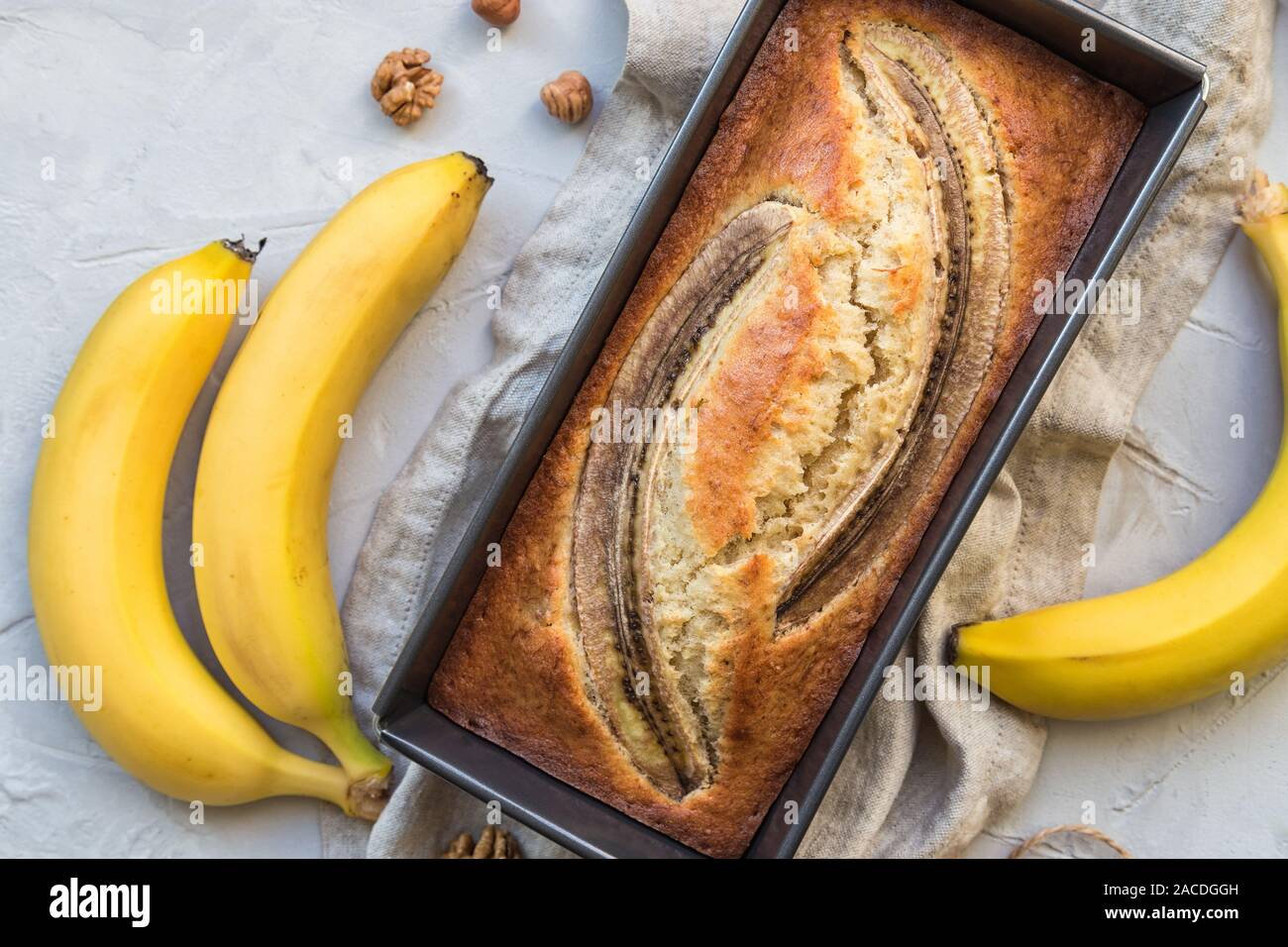 Fresh homemade banana bread in baking form on light concrete background ...