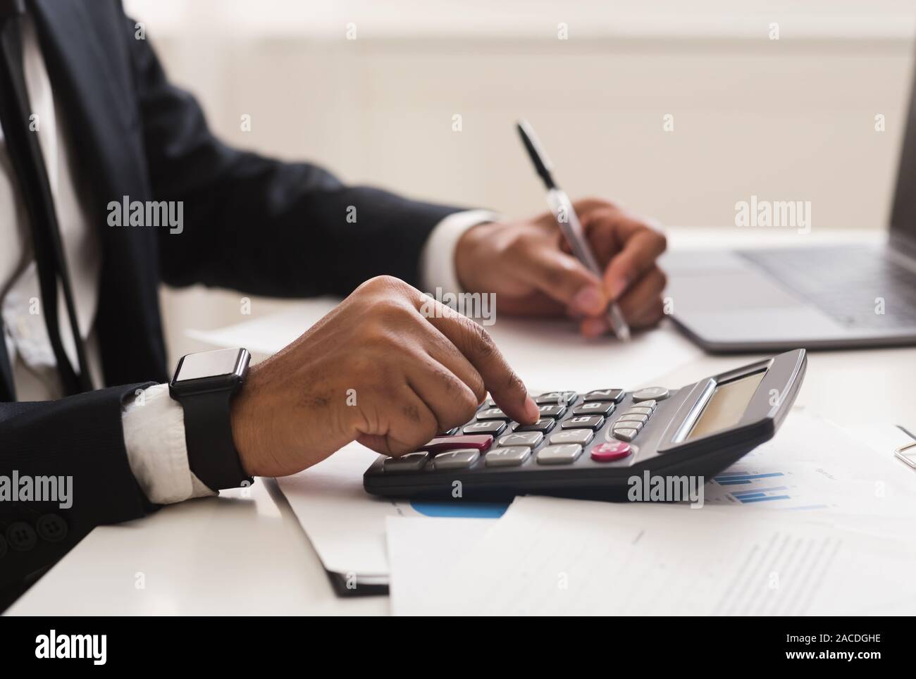 Close up of man checking on incomes, using calculator Stock Photo