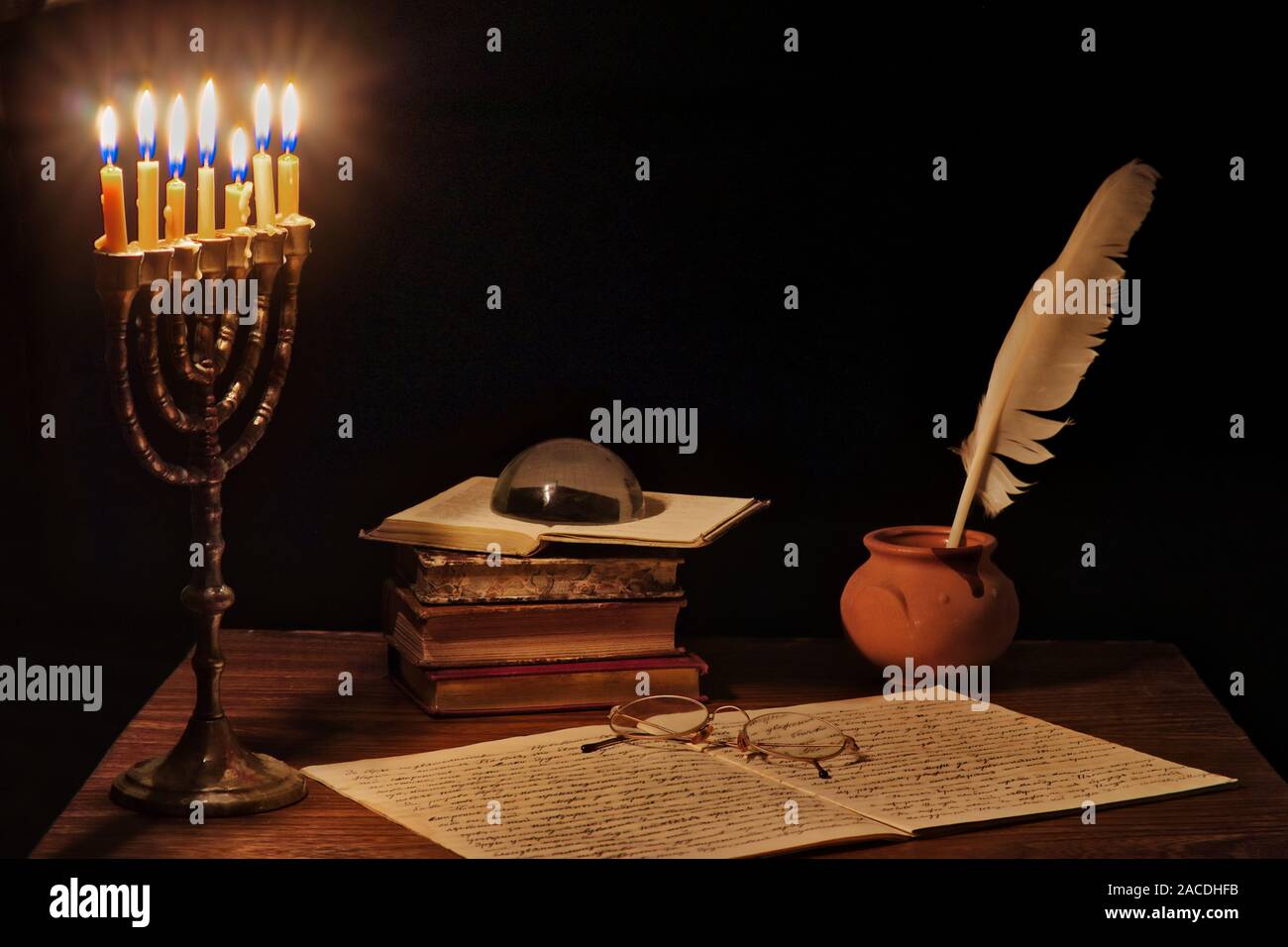 Old writing desk iluminated by menorah. Text in the notebook is in old Bulgarian ecclesiastical language and was written in the beginning of the past Stock Photo