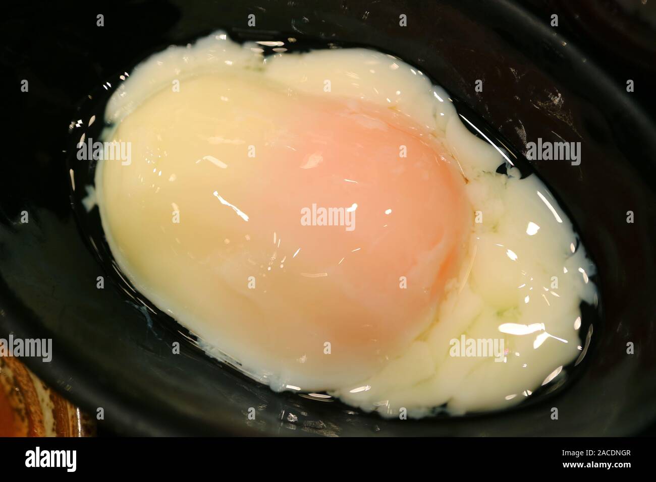 Closeup a soft-boiled egg in a black stoneware bowl Stock Photo