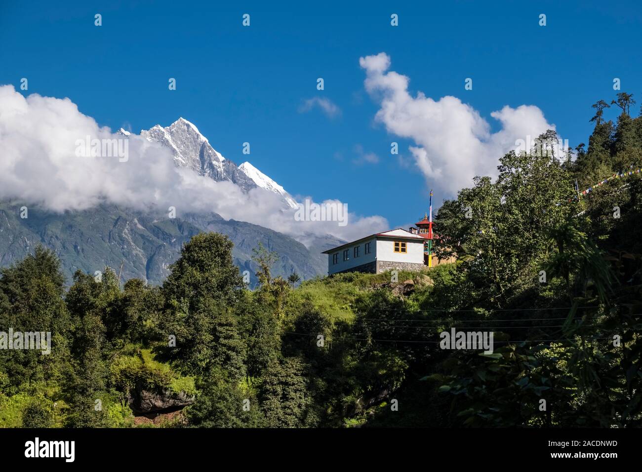 Farmers house in mountainous landscape near the pass Kari La, the summits of Numbur Himal in the distance Stock Photo
