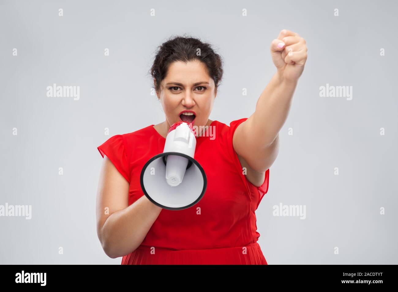 woman in red dress speaking to megaphone Stock Photo