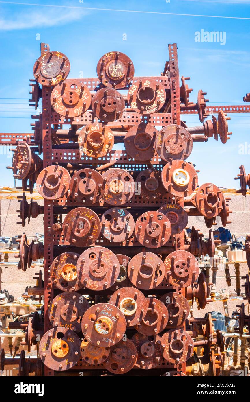 a pile of abandoned rusty wheel axles in a junk yard in the desert near