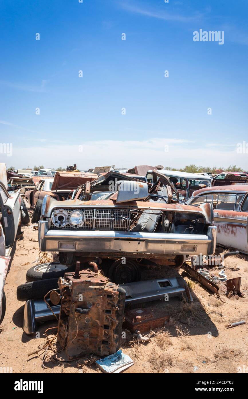 abandoned rusty cars and trucks in a junk yard in the desert near