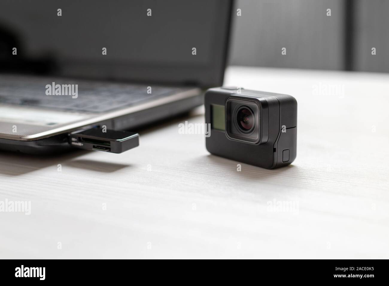 Action camera next to the laptop. Mini SD card inserted in card reader on usb port. The concept of transferring photos and videos to computer. Stock Photo