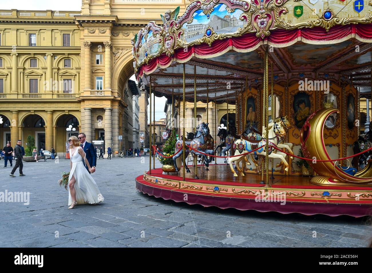 A couple of newlyweds in Republic Square in the historic centre of Florence with the old carousel and the Arc of Triumph, Tuscany, Italy Stock Photo