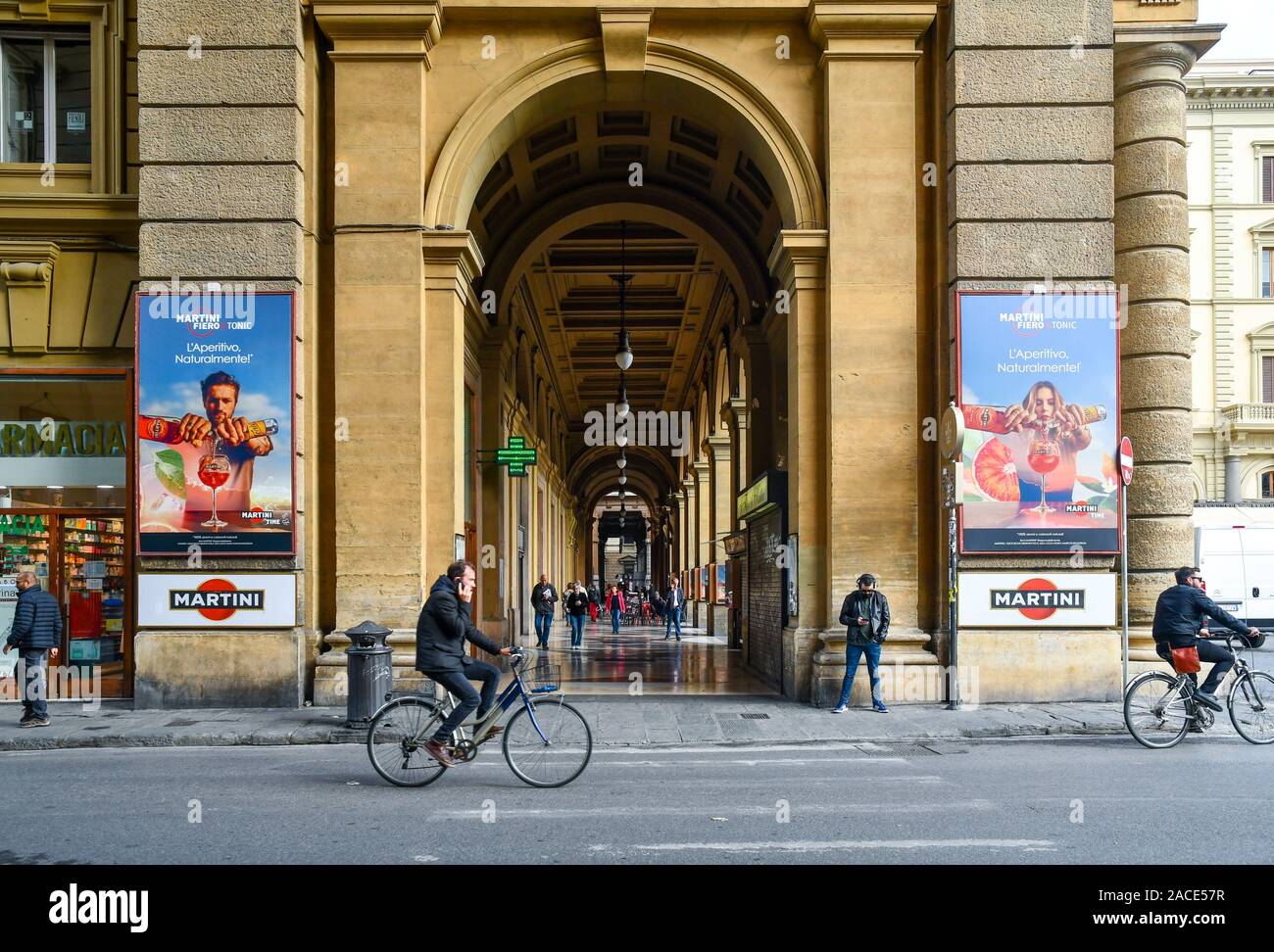 View of the arcade of Republic Square in the historic centre of Florence with people on bicycles and advertising posters, Tuscany, Italy Stock Photo