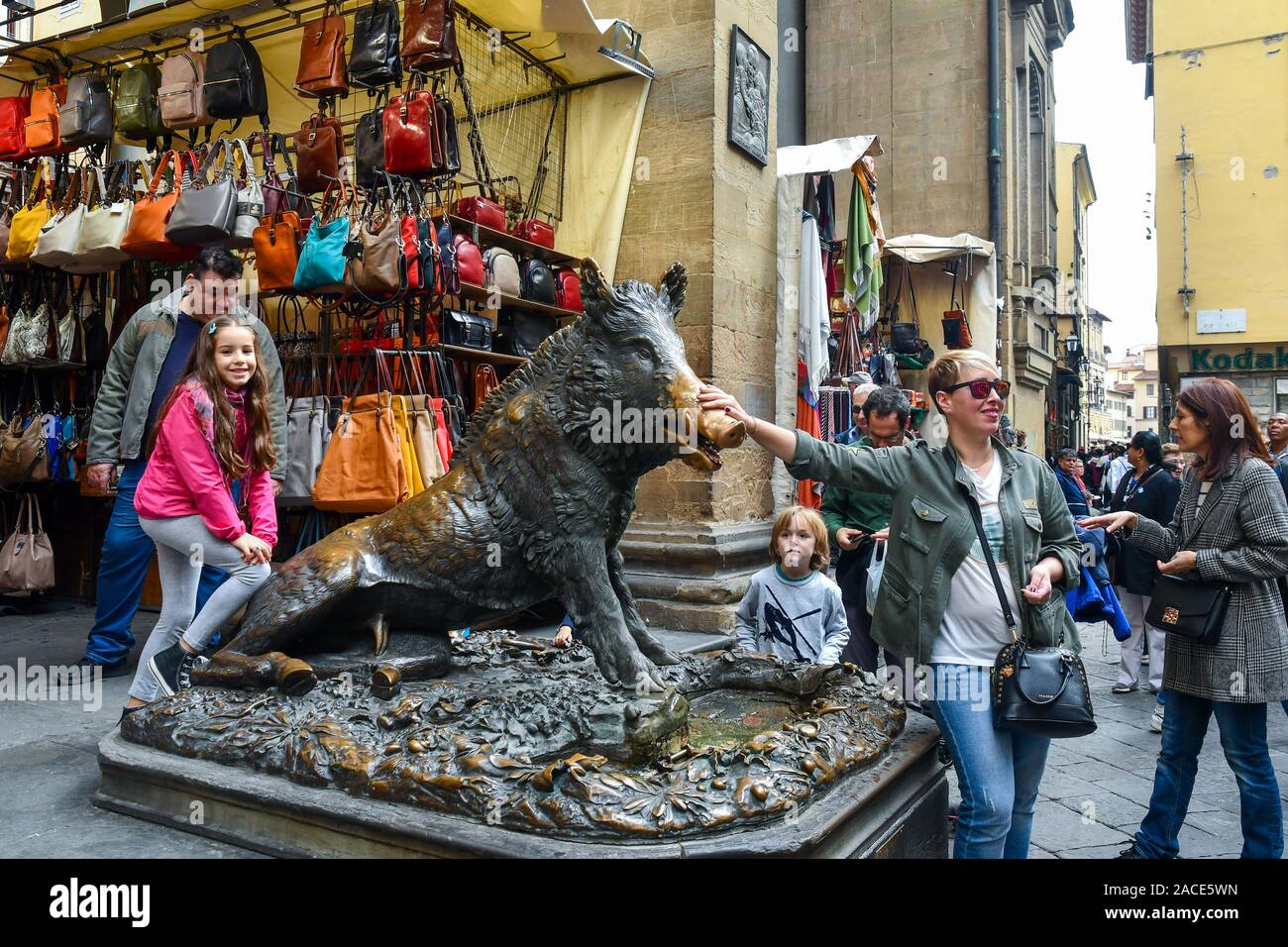 A tourist touching the nose of the 'Piggy Fountain', a gesture that is believed to bring good luck, Mercato Nuovo, Florence, Tuscany, Italy Stock Photo