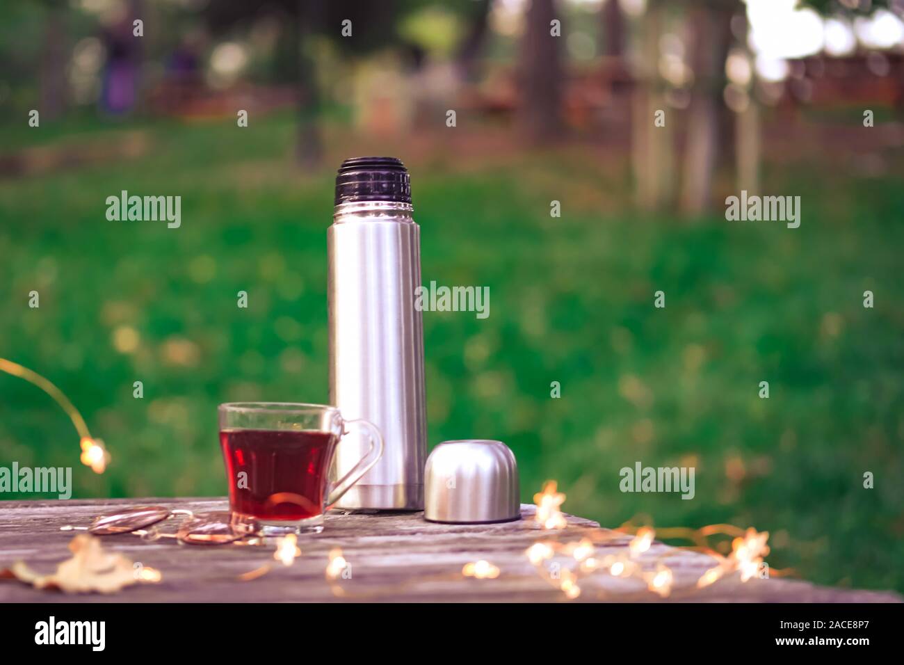 https://c8.alamy.com/comp/2ACE8P7/cozy-autumn-tea-break-with-a-cup-of-tea-thermos-flasksunglasses-and-dry-autumn-leaves-on-old-vintage-wooden-table-top-down-view-2ACE8P7.jpg