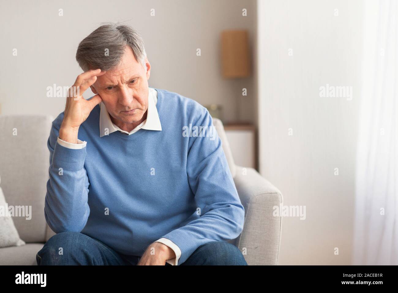 Elderly Man Thinking About Loneliness Sitting On Couch At Home Stock Photo