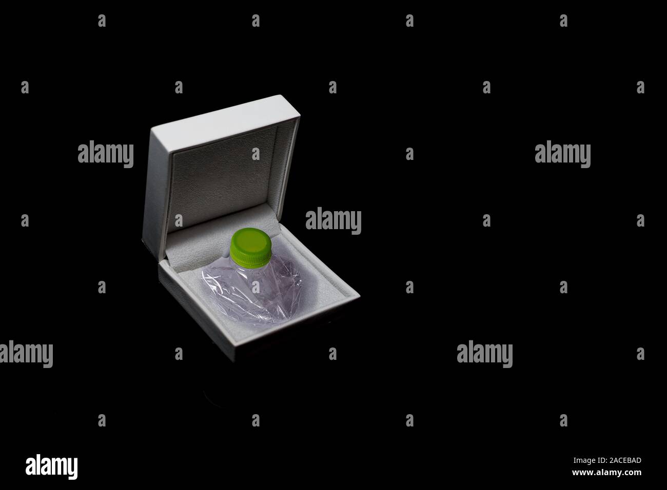 Crushed plastic bottle stored in a jewelry box on a black background Stock Photo