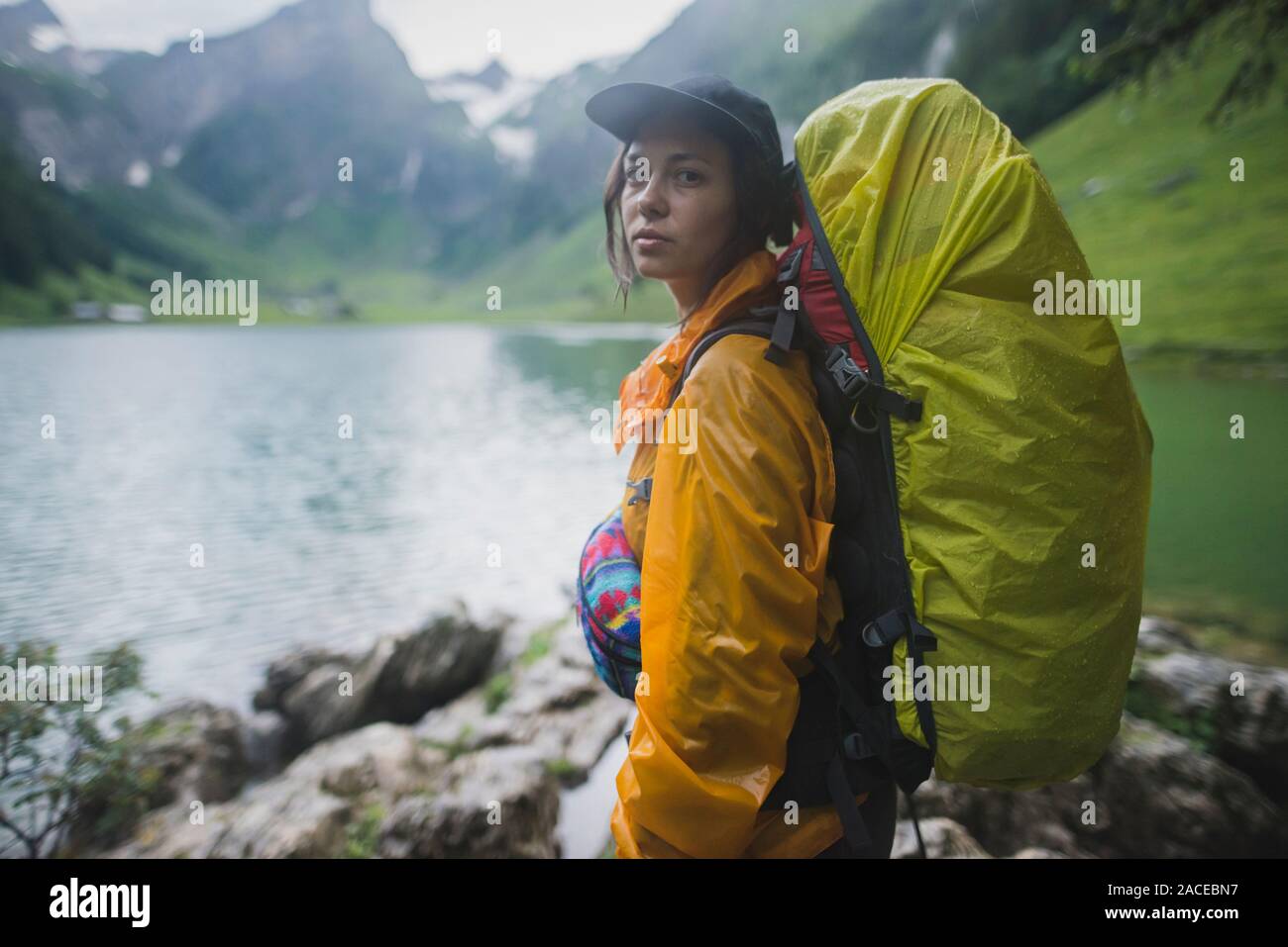 Woman wearing yellow backpack by Seealpsee lake in Appenzell Alps, Switzerland Stock Photo