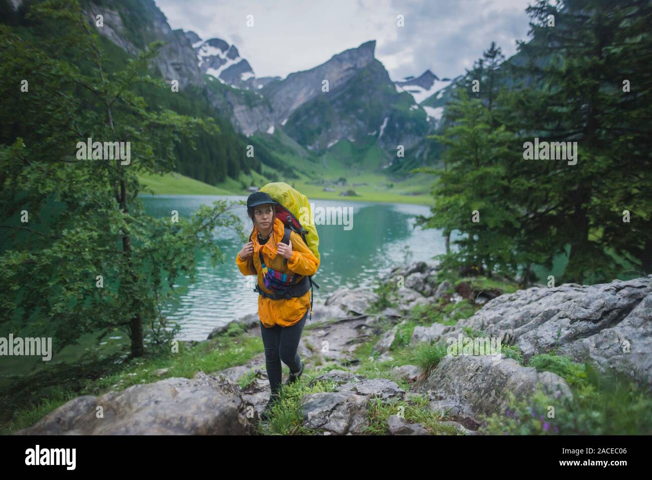 Woman wearing yellow hiking by Seealpsee lake in Appenzell Alps, Switzerland Stock Photo