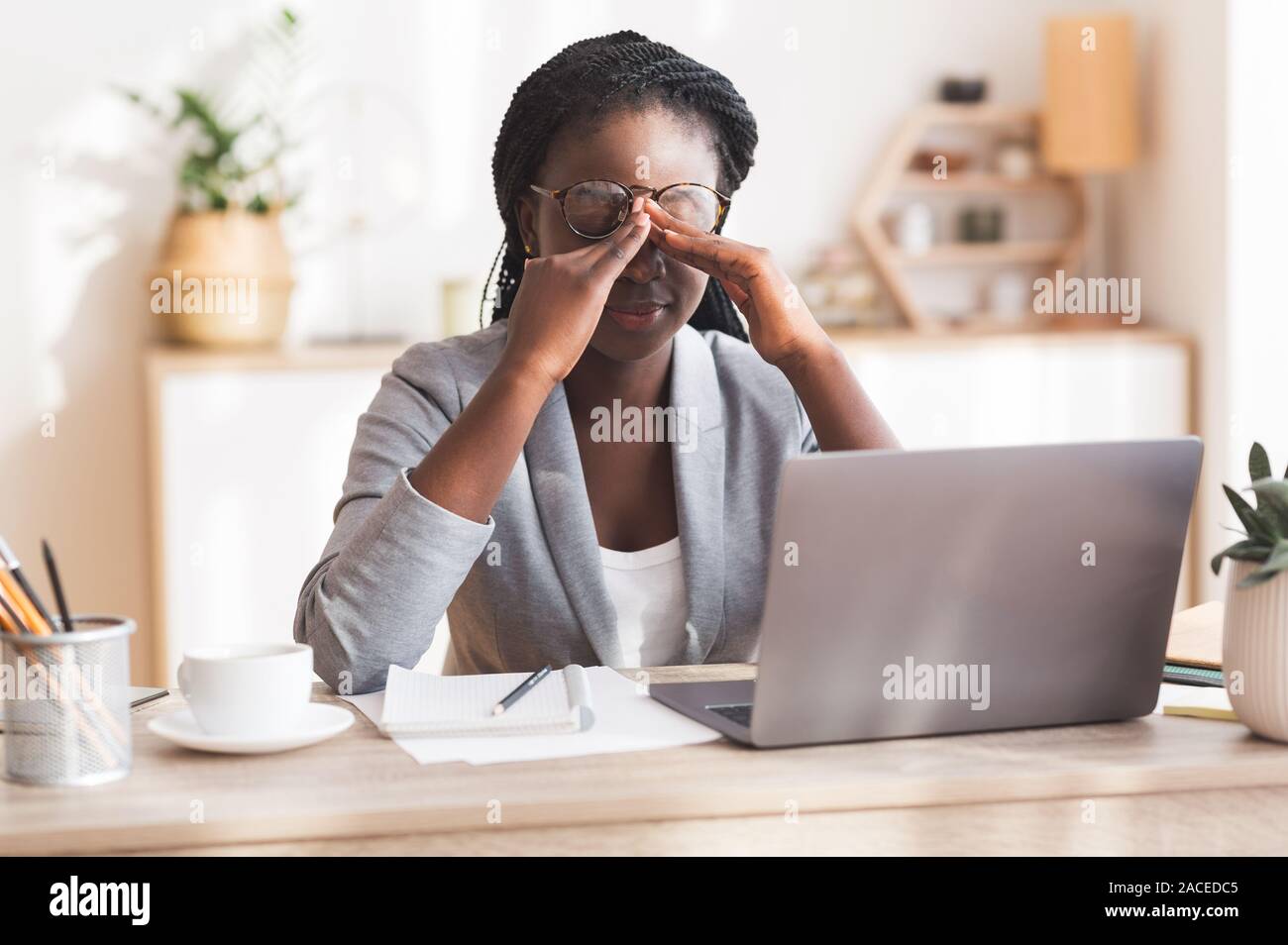 Overworked Black Businesswoman Massaging Nosebridge At Workplace Having Eyesight Problem Stock Photo