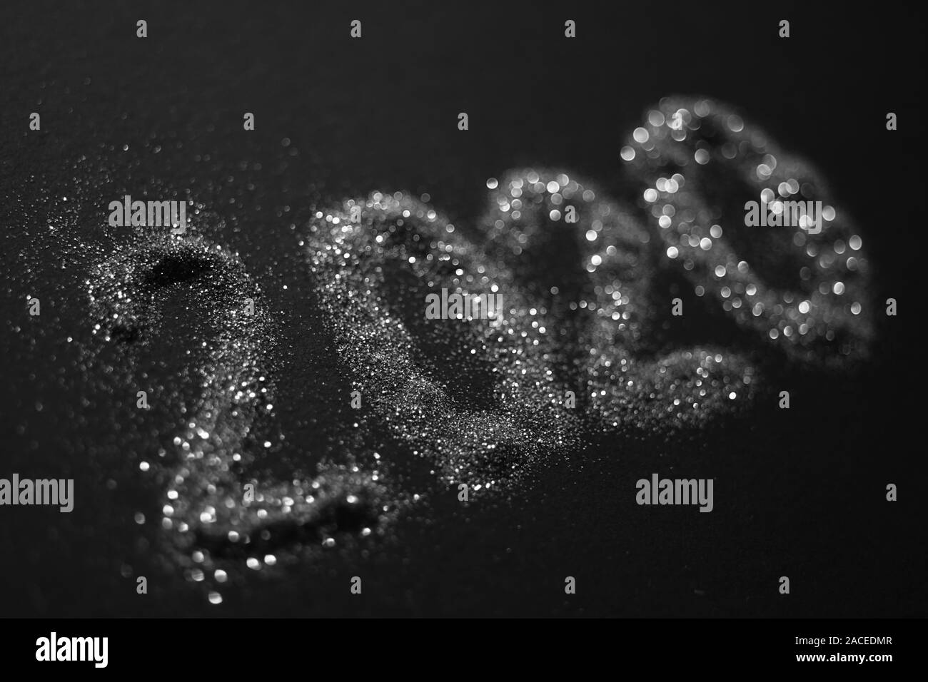 2020 shiny silver sparkles pattern on black table. Stock Photo